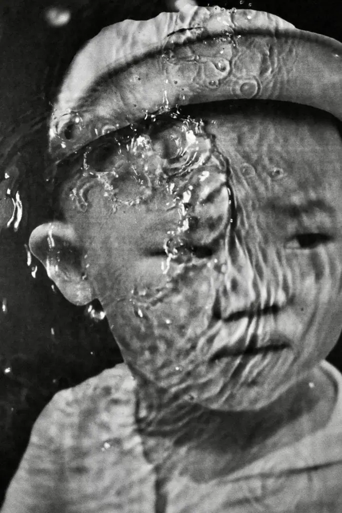 Black-and-white portrait of a child behind water droplets